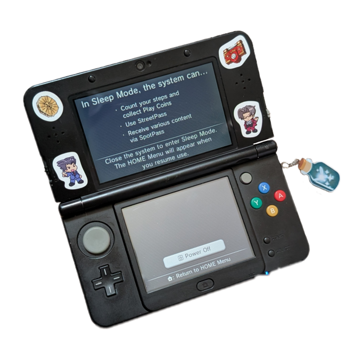 Photo of a Nintendo 3DS with Ace Attorney stickers and a Zelda fairy charm